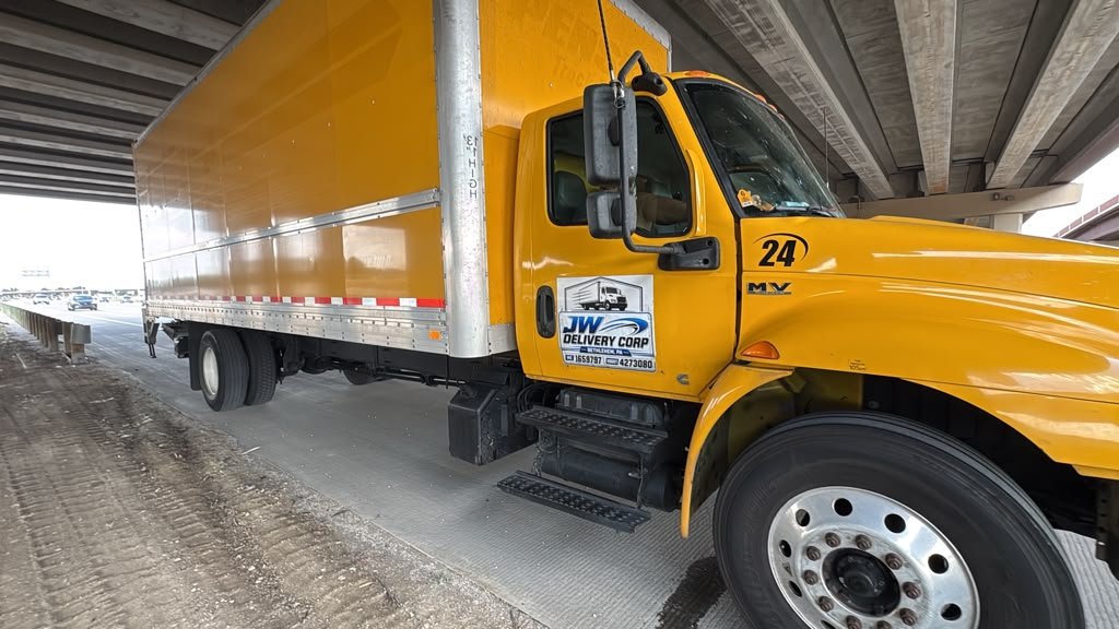 Camión amarillo de JW Delivery Corp en un punto de entrega